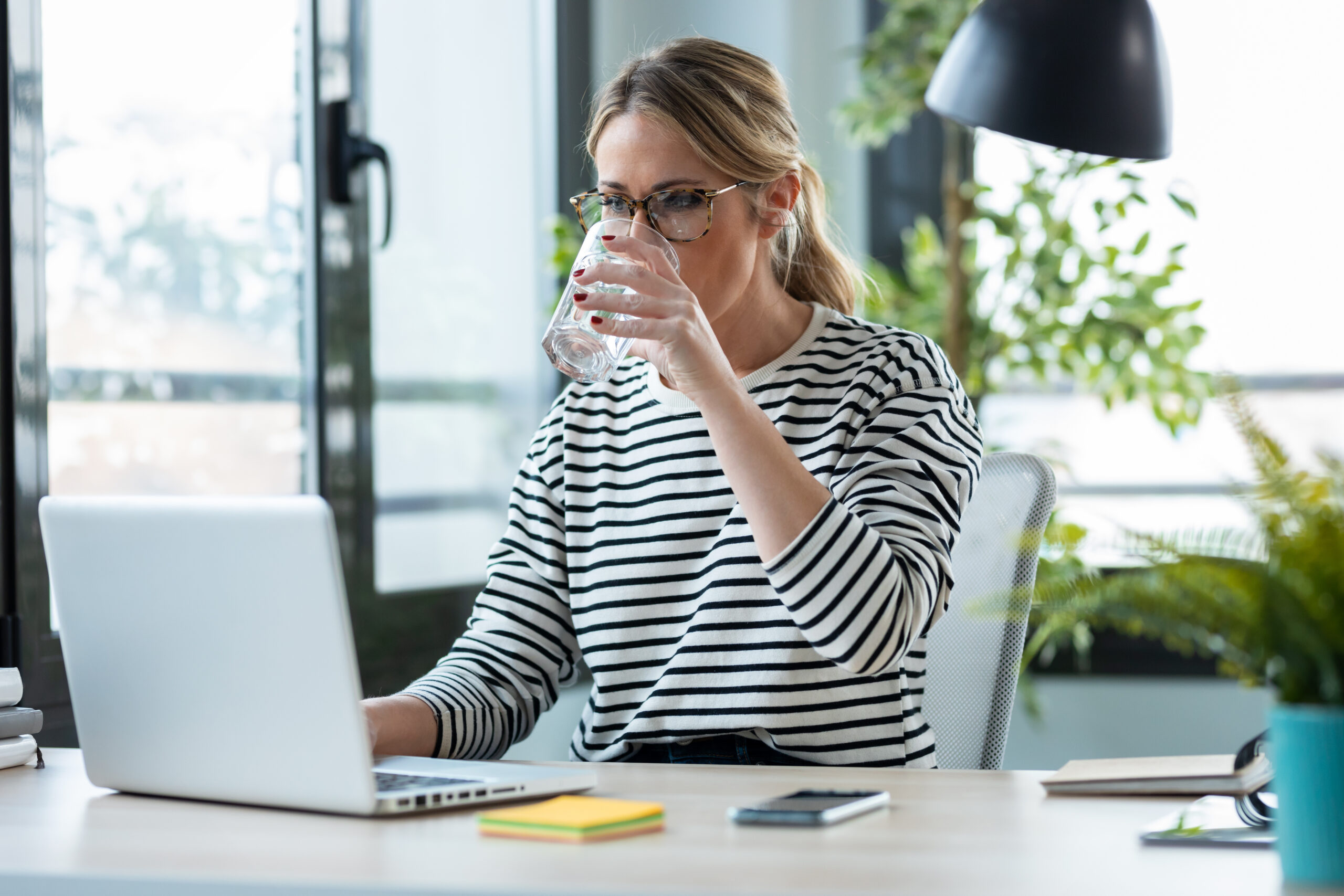 Beautiful mature business woman working with a laptop while drin
