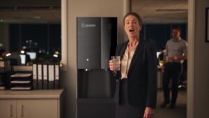 Office manager filling a glass with ice and cold water from the Aqualume Glacier in an accounting firm kitchenette